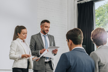 business trainers standing on stage with documents in hub