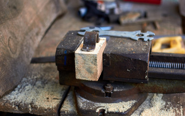 Old vice on old wooden workbench, carpenter workshop, saw, spasnner and other tools