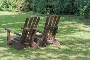 Two wooden chairs for relaxing on the green meadow in a park