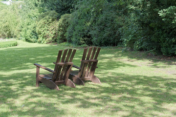 Two wooden chairs for relaxing on the green meadow in a park