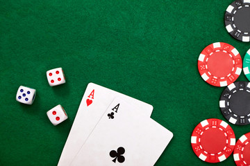 Pair of aces, dice and poker chips on green table. Casino concept.