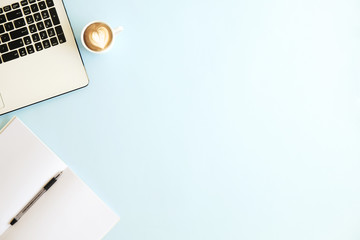 Minimalistic flat lay composition of black & white laptop computer keyboard, cell phone, coffee cup, blank page notebook on baby blue surface desk table background. Workspace top view, copy space.