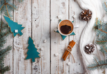 Cup of hot coffee with sugar and cinnamon on old wooden table with spruce branches.