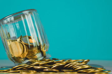 Coins stacks and gold coin money in the glass jar on table with green background, for saving for the future banking finance concept.