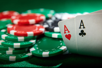 Pair of aces and poker chips on green table.