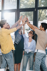 businesspeople celebrating success and giving high five in office