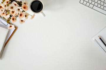 Stylish office table desk. Workspace with computer, flower and coffee mug on white wooden background. Flat lay, top view