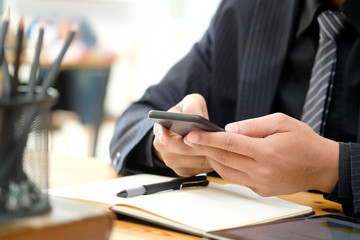 Businessman texting on mobile smart phone in office