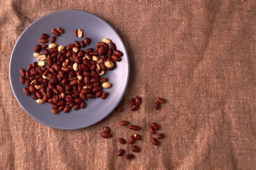 Fried Roasted peanut seed on blue plate on sackcloth background. Space for text. Copyspace