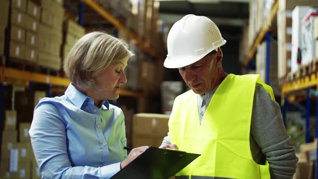 Senior woman manager talking to man worker in a warehouse.