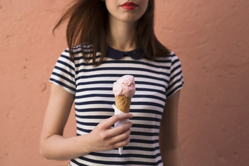 Young woman holding ice cream cone with one scoop, partial view