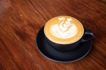 coffee cup latte art on wooden table.hot drink coffee with milk froth for breakfast.heart shape art foam texture top view.