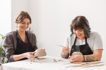 Two beautiful young women potter creating dishes