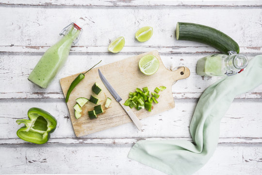 Glass bottles of homemade green Gazpacho and ingredients