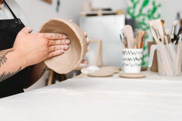 Young woman making earthen pot in pottery workshop