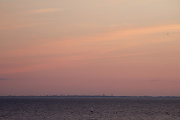 Beautiful sunset above the sea. Cumulus pink clouds in the sunset. Color clouds in the evening. Sky with a pastel colored background