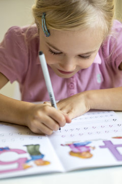Smiling little girl writing numbers in exercise book