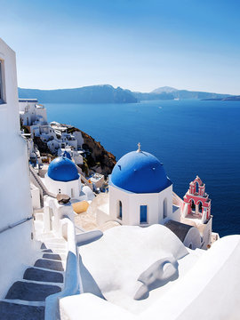 Fototapeta View with Greek orthodox church with blue domes and sea in Oia in Santorini, Greece, Europe. Beautiful scenery above the caldera overlooking the Aegean Sea.