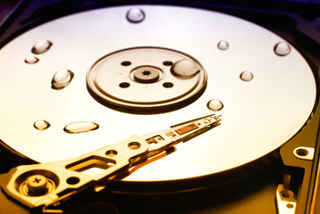 Computer hard drive with reading head and water drops on it
