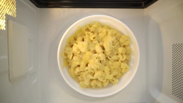 Making microwave meal. Macaroni and cheese in bowl microwaving top view.