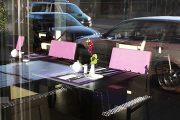 Blick durch eine Glasscheibe in ein Hotelrestaurant, Autos spiegeln sich