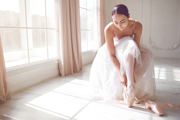 Pointe shoes on the feet of a ballerina in a white dance studio. © Studio Romantic