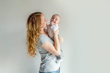 Young mother holding her newborn child. Woman and infant boy relax and playing on white background....