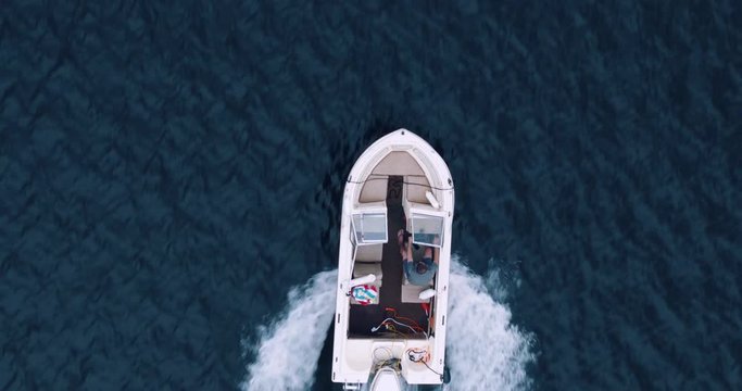 Direct overhead aerial shot of millennial man accelerating  outboard motor boat on lake