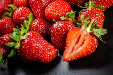 Fresh organic Strawberries on black elegant background. Sliced juicy fruit
