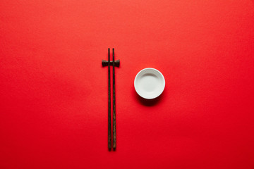 top view of arranged chopsticks and empty bowl on red backdrop