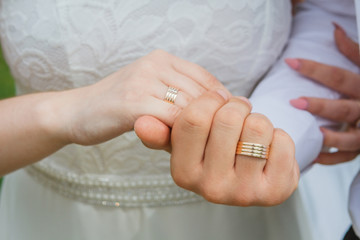 Couple holding hands with rings against wedding dress