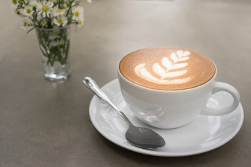 Hot coffee cup with flower on table.
