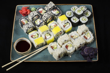 Seth sushi on a black background.Menu of the Japanese restaurant. Several sushi lined on a plate with bamboo sticks and soy sauce