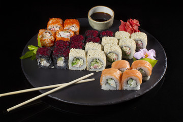 Seth sushi on a black background.Menu of the Japanese restaurant. Several sushi lined on a plate...