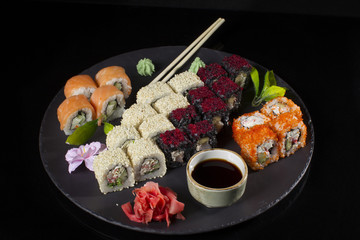 Seth sushi on a black background.Menu of the Japanese restaurant. Several sushi lined on a plate with bamboo sticks and soy sauce