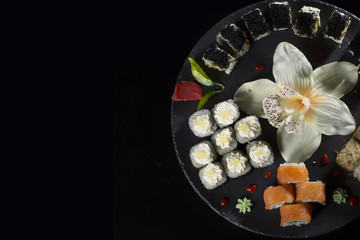 Seth sushi on a black background.Menu of the Japanese restaurant. Several sushi close-ups are beautifully laid out on a plate. Traditional Asian food