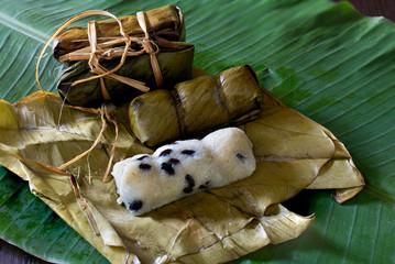 Suman, sticky rice stuffed with bananas, thai dessert on green banana leaf