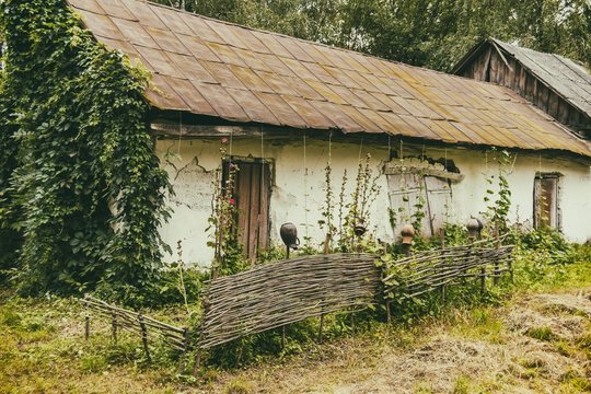 An old house with a fence in a poor village. Destroyed building.