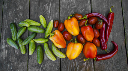 fresh vegetables, cucumbers, tomatoes, peppers, on a wooden table