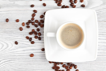 cup of coffee with coffee's beans over white wooden background, top view