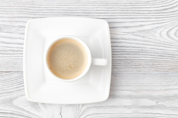 cup of coffee over white wooden background, top view