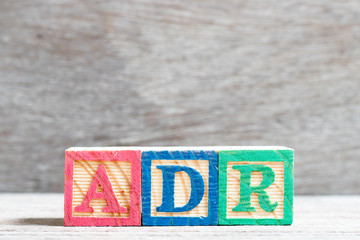Color letter block in word ADR (Abbreviation of adverse drug reaction) on wood background
