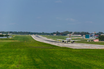 Fototapeta premium airplane on runway, green grass, blue sky