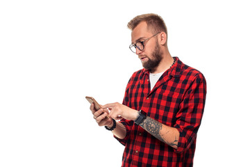Message to friend. Handsome young man using phone while standing againstwhite background