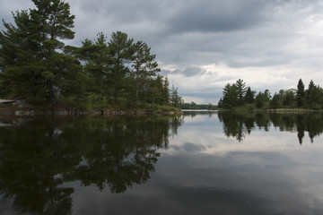 Reflection of trees and clouds in a lake, Lake of The Woods, Ontario, Canada