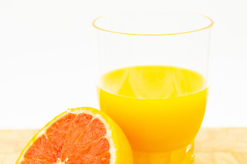 Arancia o pompelmo vicino ad un bicchiere di succo d'arancia su un tavolo di legno