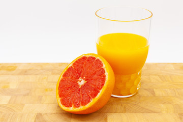 Arancia o pompelmo vicino ad un bicchiere di succo d'arancia su un tavolo di legno