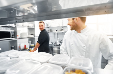 Fototapeta na wymiar cooking food, profession and people concept - happy male chef and cook at restaurant kitchen