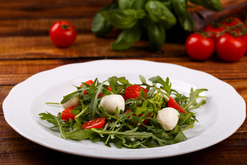 Healthy salad with mozarella cheese tomato arugula and balsamic dressing, close up