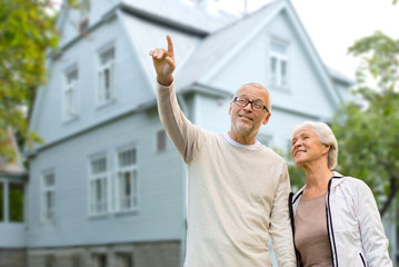 old age, accommodation and real estate concept - happy senior couple over living house background